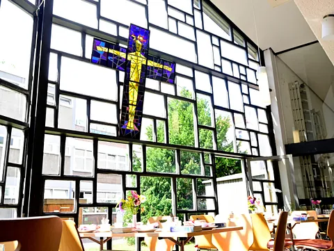 Buntglas-Christus am Kreuz in moderner Kirche.