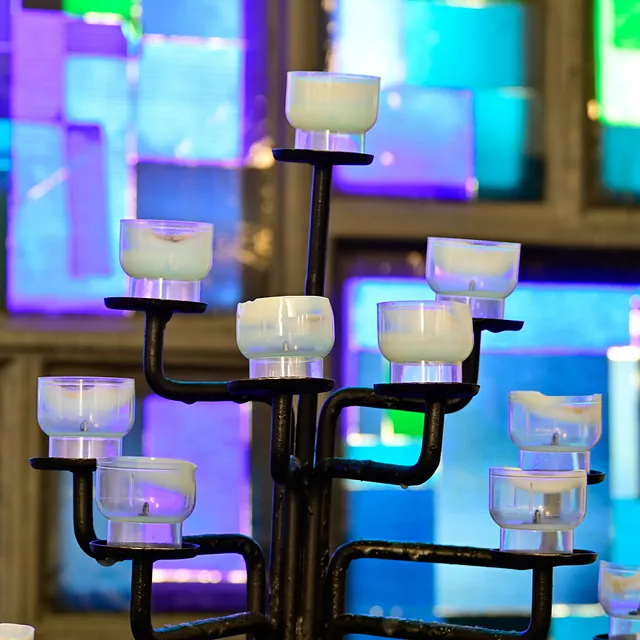 Kirchenkerzen leuchten, farbige Glasfenster.