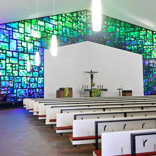 Leuchtende Buntglaswände in modernem Kirchenraum.
