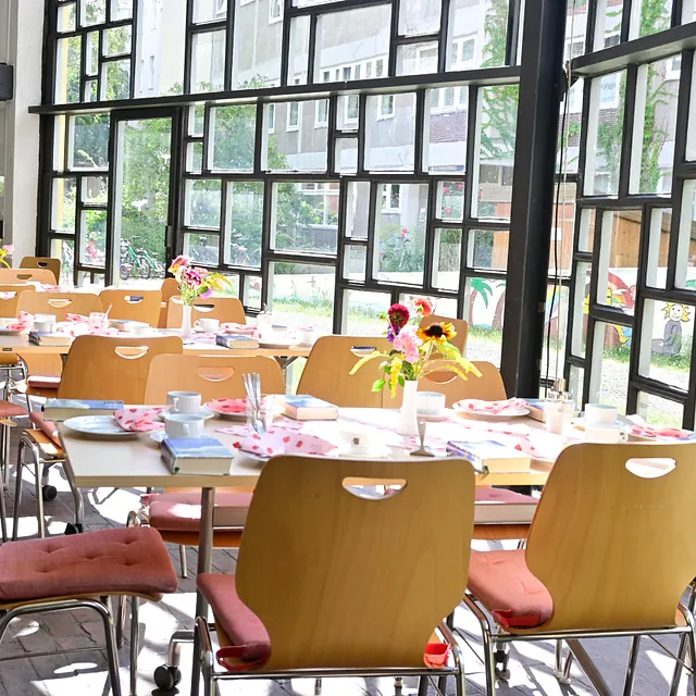 Heller Gemeindesaal mit für Mahlzeit gedeckten Tischen.
