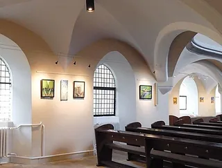 Kunstausstellung in Kirchenschiff mit Gewölbedecke.
